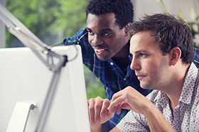 Photo of two young men working on a computer